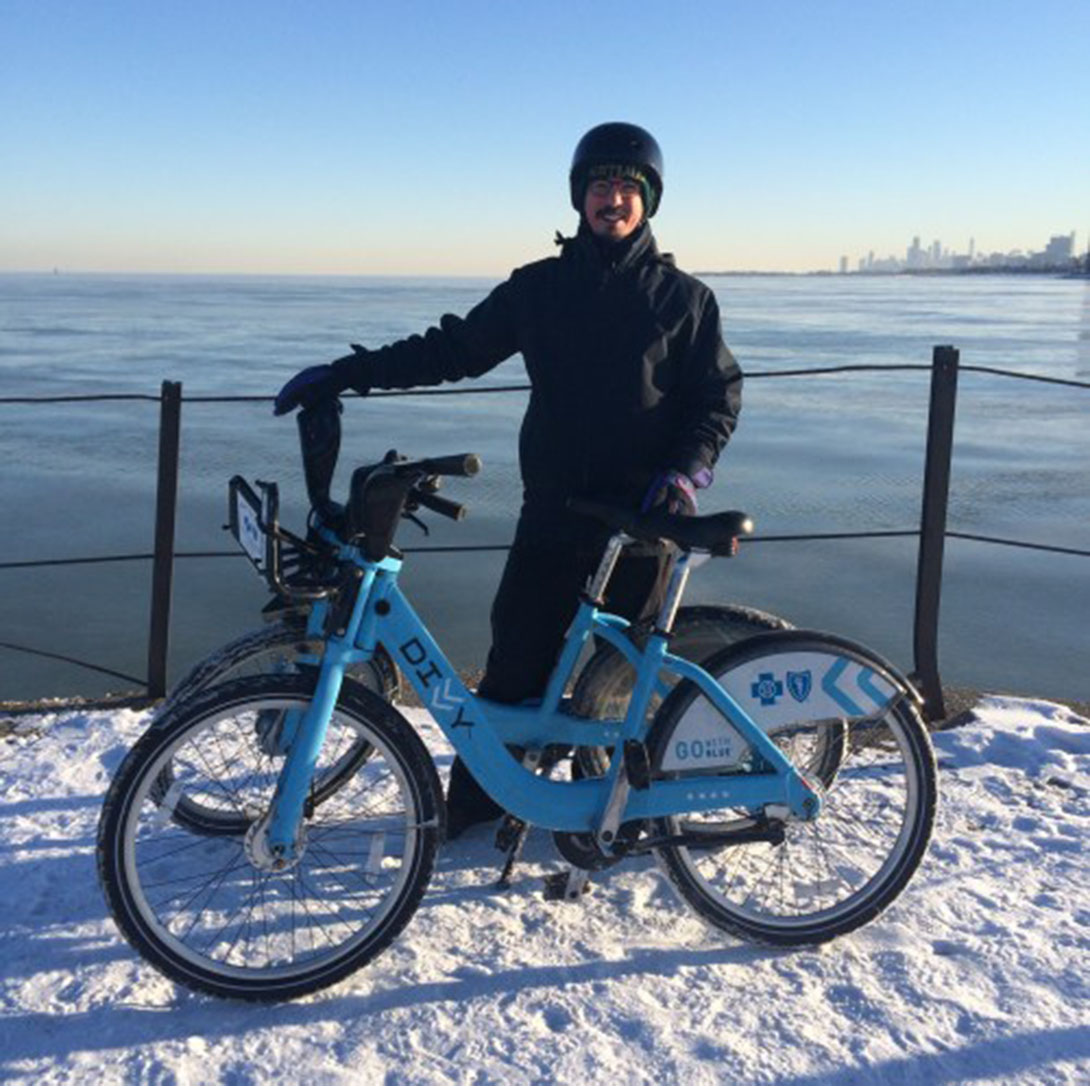 Alvaro Villagran dressed in winter bike riding gear with divvy bike
                  