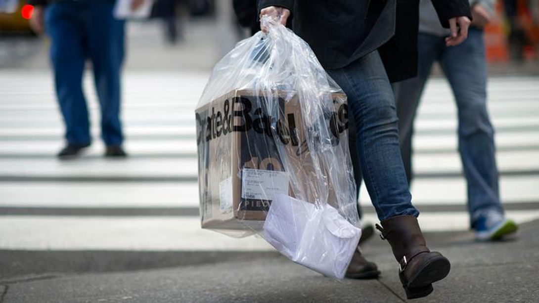 person walks down street with retail shopping bag
                  