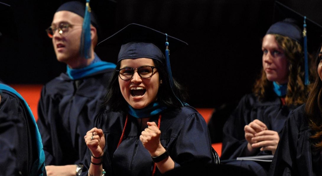 A very happy student celebrating her commencement with clenched fists and verbalizing YES!