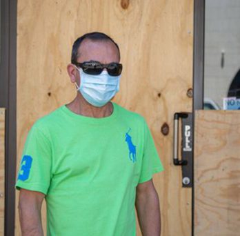 Store owner in front of boarded up windows
                  