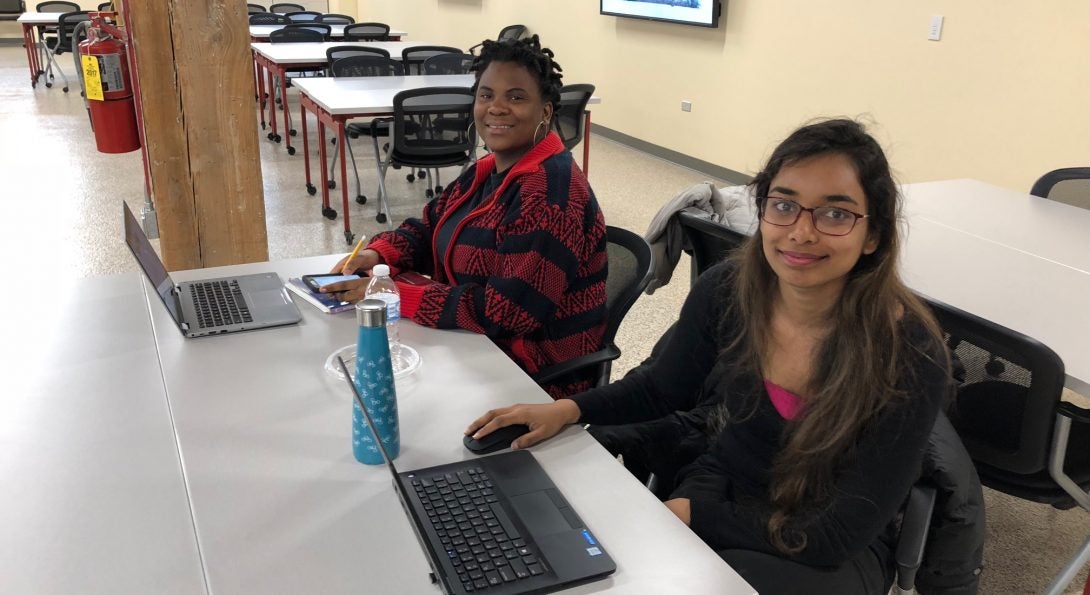 Two students working at tables in the Lower Level of CUPPA Hall