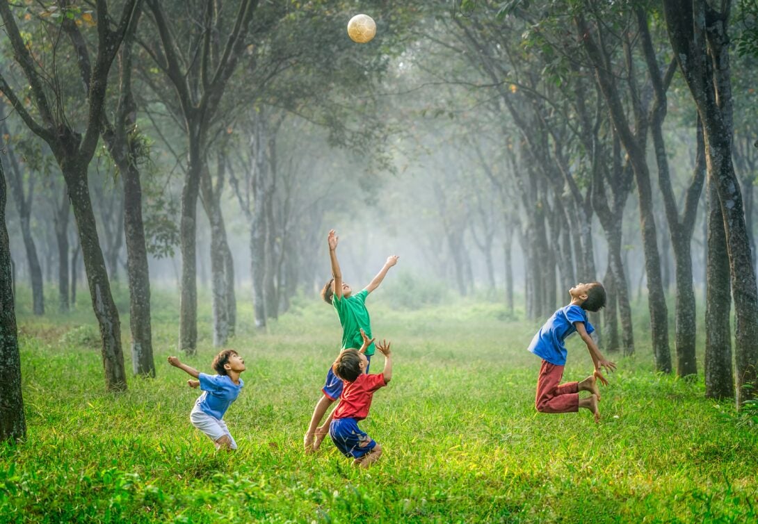 Four boys playing ball in a field and having fun