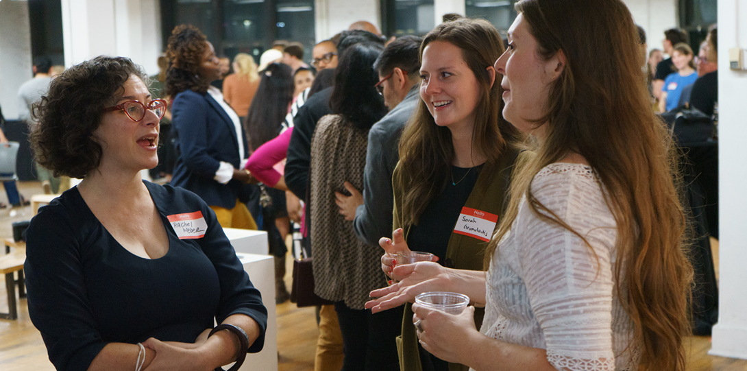 three women stand talking to each other at a networking event