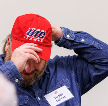 UIC CUPPA Alumnus Josh Deth dons a UIC baseball cap prior to the fall commencement 2023 ceremony. 