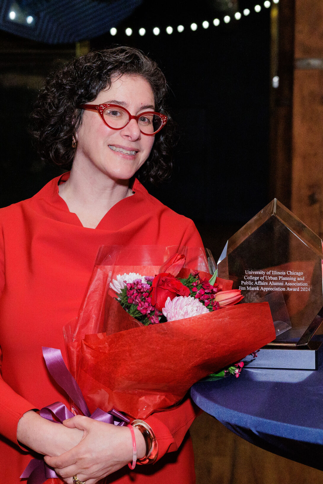 Rachel Weber with a bouquet of flowers and her Jim Marek Award, a glass design in the shape of a flame.