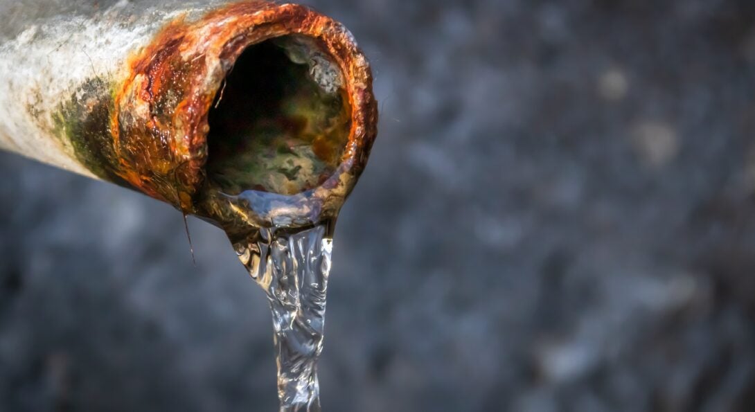 water flowing gently out of a rusty lead pipe.