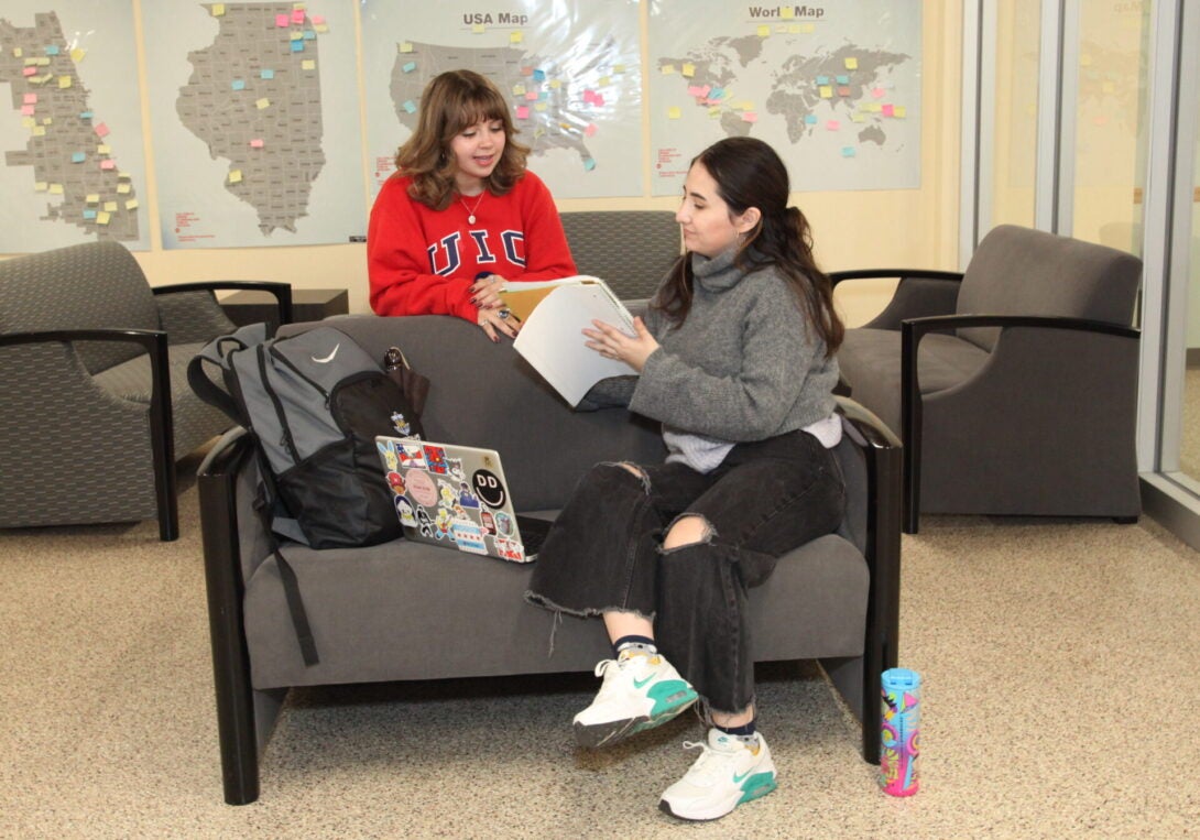 Two Students Studying and Taking Notes while sitting on a sofa in the Lower Level of CUPPA Hall