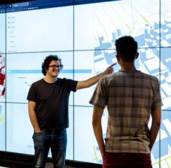 Fabio Miranda is an Assistant Professor at the Department of Computer Science at the University of Illinois Chicago. He is standing in front to a code generated map. 