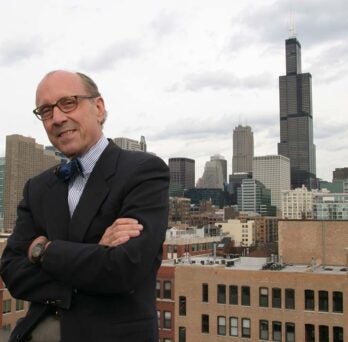 Dr. David Perry posing on the rooftop of CUPPA Hall with the city of Chicago loop in the background. 