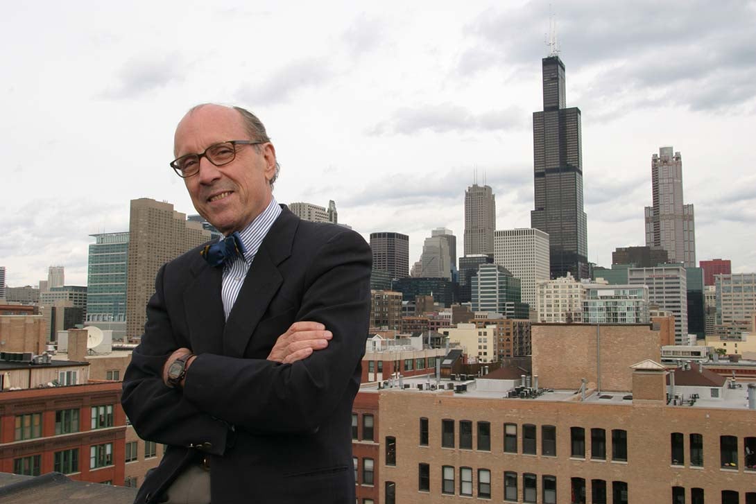 Dr. David Perry posing on the rooftop of CUPPA Hall with the city of Chicago loop in the background.