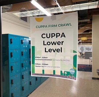 Firm Crawl Poster hanging on the glass door entry to the Lower Level of CUPPA Hall with the student blue mailboxes beyond the doorway. 